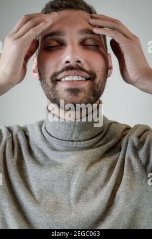 Un giovane con una barba corta tocca i suoi templi un momento di relax Foto Stock