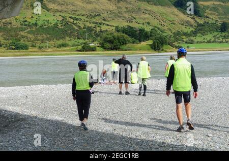 Otago Nuova Zelanda - 3 marzo 2015; i ciclisti che escono dall'ombra del ponte verso il letto panoramico sassoso del fiume Dart al ponte te Araroa Trail e p. Foto Stock