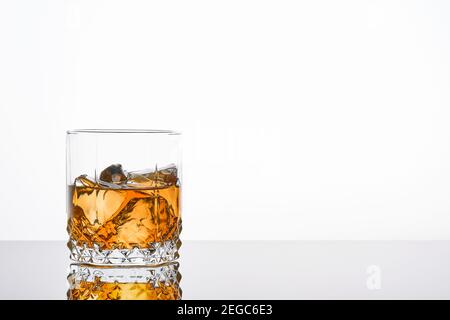Whisky con ghiaccio o brandy in vetro con sigaro su sfondo bianco. Whisky con ghiaccio in vetro. Whisky o brandy. Messa a fuoco selettiva.