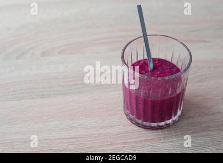 Cocktail di mirtillo (frullato) in un bicchiere con un cucchiaio di metallo su un tavolo di legno Foto Stock