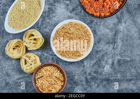 Vari tipi di pasta secca sullo sfondo marmoreo Foto Stock