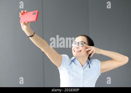 Donna con occhiali che sorridono e prendono selfie Foto Stock