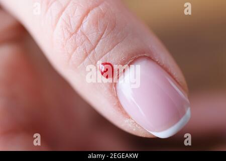 Closeup di goccia di sangue vicino al chiodo di womans Foto Stock