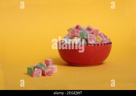 Ciotola rossa di rahat Lakoum isolato su sfondo giallo. Dolce concetto turco. L'immagine contiene spazio per la copia Foto Stock