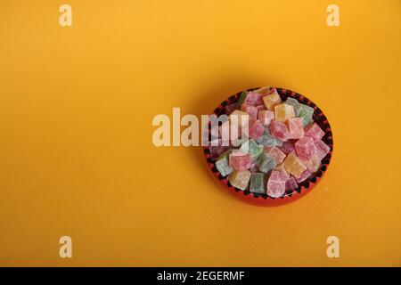 Ciotola rossa di Lakoum rahat isolata su fondo giallo flst lay. Dolce concetto turco. L'immagine contiene spazio per la copia Foto Stock