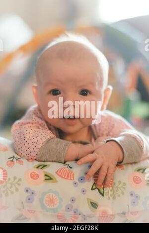 Bambina di tre mesi che si tiene su un cuscino Foto Stock