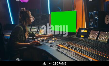 Ritratto di elegante femmina Audio Engineer Produttore che lavora in Music Record Studio, utilizza schermo verde computer Display, Mixer Board, Control Desk a. Foto Stock