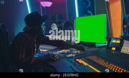 Elegante produttore audio che lavora in Music Record Studio, utilizza Green Screen Chroma Key computer Display, Mixer Board Equalizer e Control Desk per creare Foto Stock