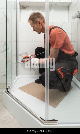 Il lavoratore sta sigillando il box doccia con silicone per evitare perdite  Foto stock - Alamy