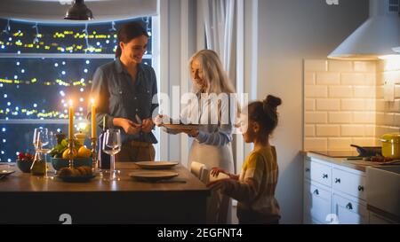 Multi generazioni di belle donne che preparano e servono la cena in cucina. Nonna, figlia e nipote carino hanno divertimento, cucina Foto Stock