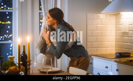 Belle donne che preparano e servono la cena in cucina. La madre anziana abbracca la figlia matura. Hanno divertimento, cucinare insieme, parlare, Gossip, condividere Foto Stock