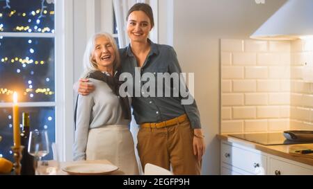 Multi generazioni di belle donne in cucina. Madre anziana e figlia matura abbraccio, divertirsi e sorridere sulla fotocamera. Deliziosa cena in famiglia con Foto Stock