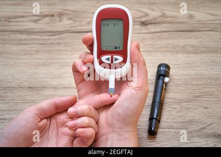 Misurazione della glicemia con glucometro a casa. Una goccia di sangue e glucometro. Controllo dello zucchero nel sangue. Foto Stock