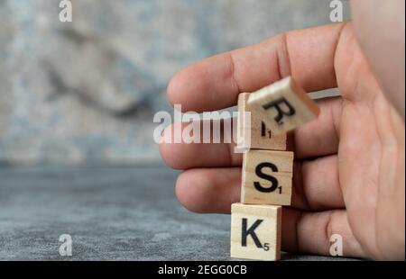 Rischio di scrittura con lettere nere su morse di legno e un uomo che lo tiene con la mano Foto Stock