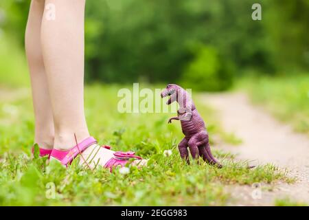 Bambina che gioca con il giocattolo di plastica dei dinosauri in primavera parcheggio Foto Stock