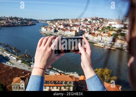 Una ragazza sta fotografando un panorama della città di Porto, in Portogallo. Fotografia mobile Foto Stock