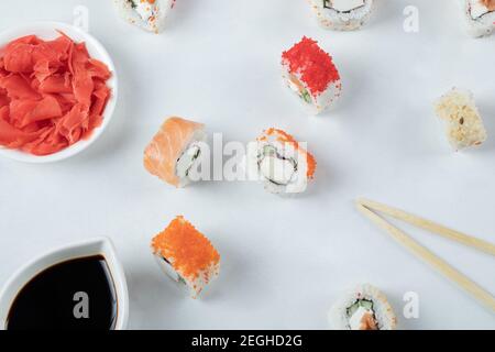 Panini di sushi con salmone e caviale serviti con salsa di soia su sfondo bianco Foto Stock
