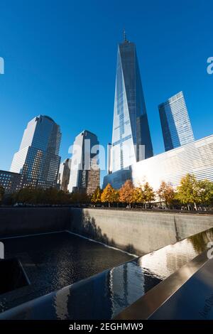 Il sole illumina le file di alberi di colore autunnale che circondano la piscina Memorial South nel National September 11 Memorial a Lower Manhattan. Foto Stock