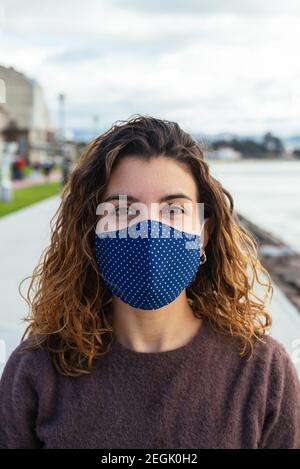 Giovane donna sulla strada che indossa una maschera facciale Foto Stock