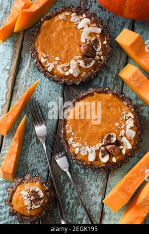 Dessert autunnale. Tartine vegetariane di zucca con noci e avena su sfondo blu shabby con zucca cruda sopra la vista Foto Stock