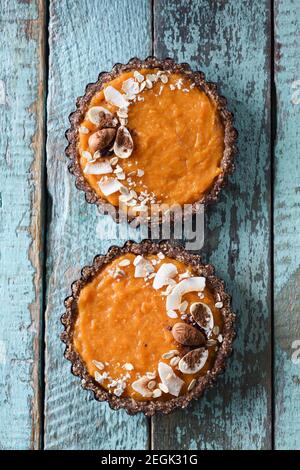 Dolci vegani. Tartine di zucca fatte in casa con noci, cacao e cocco su tavole di legno blu shabby sopra la vista Foto Stock