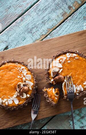 Sano dessert vegetariano. Torte di zucca aperte con noci e farinata d'avena su tavola di legno su sfondo blu copyspace Foto Stock