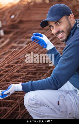 lavoratore di costruzione che tiene barre di rinforzo di calcestruzzo Foto Stock