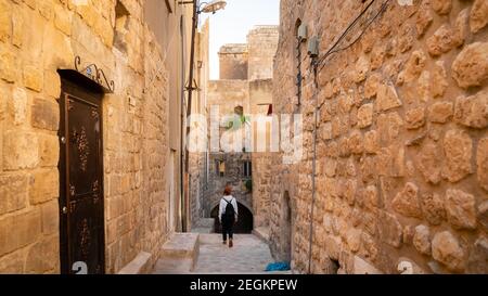 Mardin, Turchia - Gennaio 2020: Donna turistica che cammina in una stretta strada di pietra della città vecchia di Mardin Foto Stock