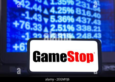 In questa illustrazione fotografica viene visualizzato un logo GameStop su uno smartphone con l'immagine del mercato azionario sullo sfondo. Foto Stock