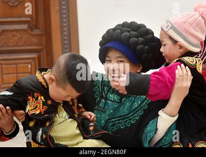 (210219) -- PECHINO, 19 febbraio 2021 (Xinhua) -- Bamu Yubumu gode di tempo libero con i suoi bambini a casa nella contea di Yuexi nella prefettura autonoma di Liangshan Yi nella provincia sudoccidentale del Sichuan, 16 febbraio 2021. Bamu Yubumu era conosciuta come una madre migrante in una foto iconica durante una corsa di corsa di viaggio del Festival di primavera 11 anni fa. Recentemente, lei e suo marito Wuqi Shiqie hanno intrapreso la loro nuova carriera di coltivazione di cetrioli marini nella provincia costiera del Fujian. Durante la festa primaverile di quest'anno, Bamu e suo marito tornarono nella loro città natale nel Sichuan della Cina sud-occidentale per una visita. Foto Stock