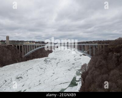 Rainbow bridge presso le cascate del Niagara, confine tra America e Canada sul fiume primaverile coperto di ghiaccio su un colato giorno Foto Stock