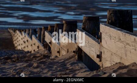 Un groyne di legno su una spiaggia con sabbia e mare Foto Stock