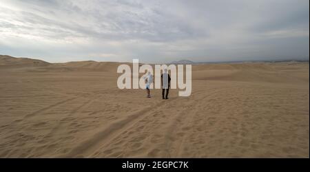 Perù, Ica - 21 settembre 2019 - due turisti volano un drone al deserto, pneumatici tracce sulla sabbia Foto Stock