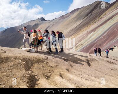 Perù, Vinicunca - 27 settembre 2019 - i turisti asiatici prendono selfie con lama sulla montagna arcobaleno Foto Stock