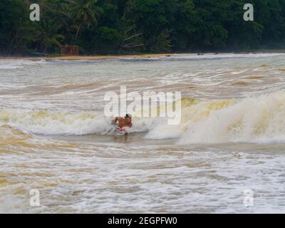 Puerto Viejo, Costa Rica - 30 novembre 2019 - giovane uomo body boarding dove il fiume incontra l'oceano Foto Stock