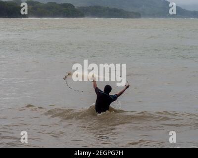 Puerto Viejo, Costa Rica - 30 novembre 2019 - giovane uomo gettato rete di pesca all'interno dell'acqua Foto Stock