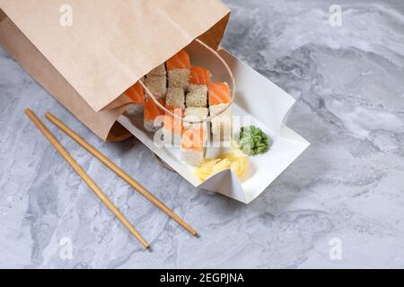 Scatola da asporto con rotoli di sushi in sacchetto di carta marrone. Concetto di sushi to go. Foto Stock