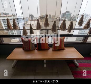 Perù, Lima - 28 settembre 2019 - tasselli appesi di fronte alla finestra di vetro, panca con cuscini di colore brillante Foto Stock