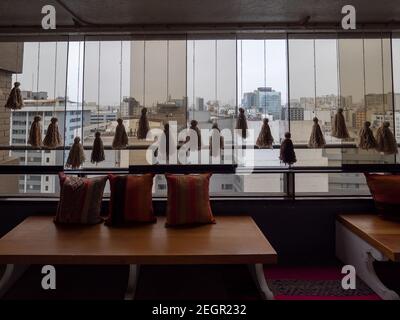 Perù, Lima - 28 settembre 2019 - Lima città vista attraverso la finestra di vetro, cuscini di colore luminoso su panca, tassels appeso al soffitto Foto Stock