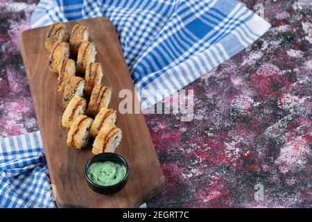 Panini fritti di sushi su una tavola di legno serviti con wasabi salsa Foto Stock