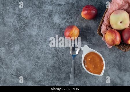 Pesche e mele in un cesto di legno su un pezzo di asciugamano rosa Foto Stock