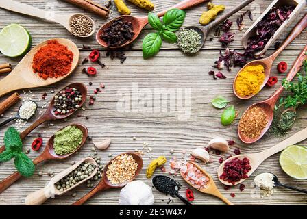 Una selezione di varie spezie colorate su un tavolo di legno in cucchiai Foto Stock