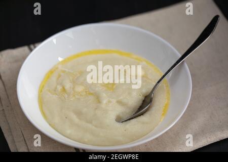 Porridge di semola o panna di grano in piastra bianca con latte e burro. La colazione è pronta Foto Stock