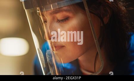 Primo piano Ritratto di bella Femminile Fabricator in maschera di sicurezza. Sta macinando un oggetto metallico. Potenziare la bellezza naturale lavorando in un laboratorio. Foto Stock