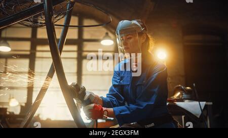 Primo piano Ritratto di bella Femminile Fabricator in maschera di sicurezza. Sta macinando un oggetto metallico e Flying Hot Sparks riflettere sulla maschera. Potenziamento Foto Stock