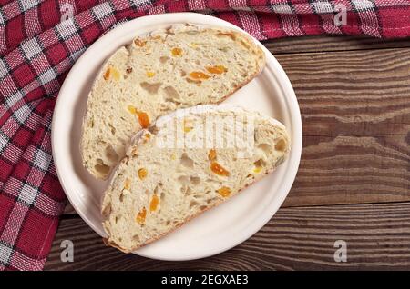 Due fette di pane di ciabatta con albicocca secca e semi di zucca in piastra su tavolo di legno, vista dall'alto Foto Stock