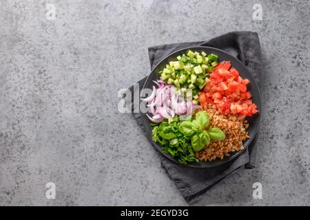 Farro di cereali interi con verdure fresche diverse da mescolare su tavola grigia. Vista dall'alto. Foto Stock