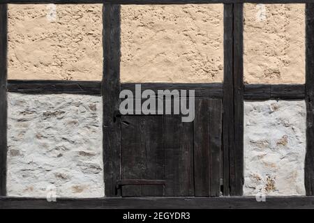 Antico dettaglio a graticcio di un fienile con un piccolo legno porta Foto Stock