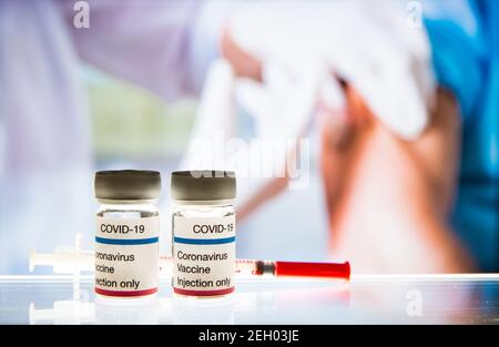 Primo piano del vaccino COVID-19. Medico femminile con maschera chirurgica e in guanti che danno iniezione di vaccino all'uomo in ospedale. Vaccinazione durante il coronavirus Foto Stock