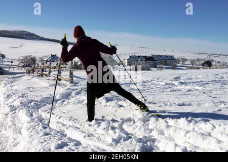Paesaggio innevato con donna sciatrice in neve Repubblica Ceca donna che cammina in campagna inverno pali da passeggio vista posteriore Foto Stock